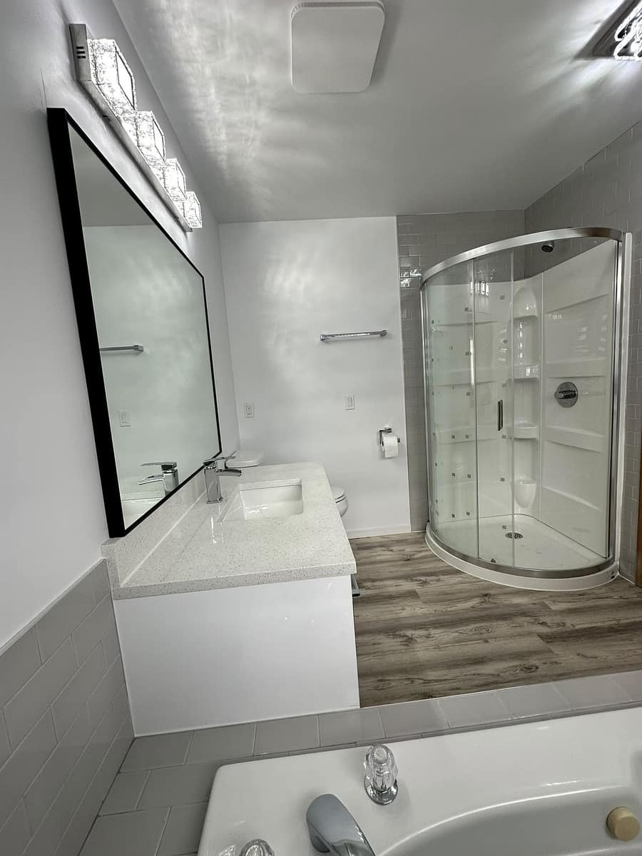 Bathroom Renovation (Tamarack) — finished vanity with black-framed mirror and glass corner shower enclosure