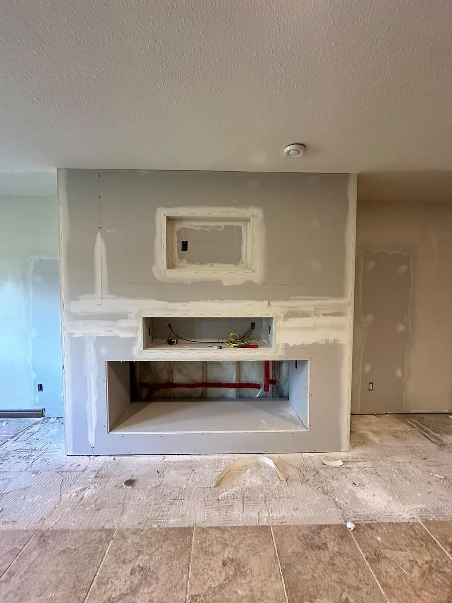 Bungalow Home Renovation — custom basement fireplace feature wall during drywall finishing