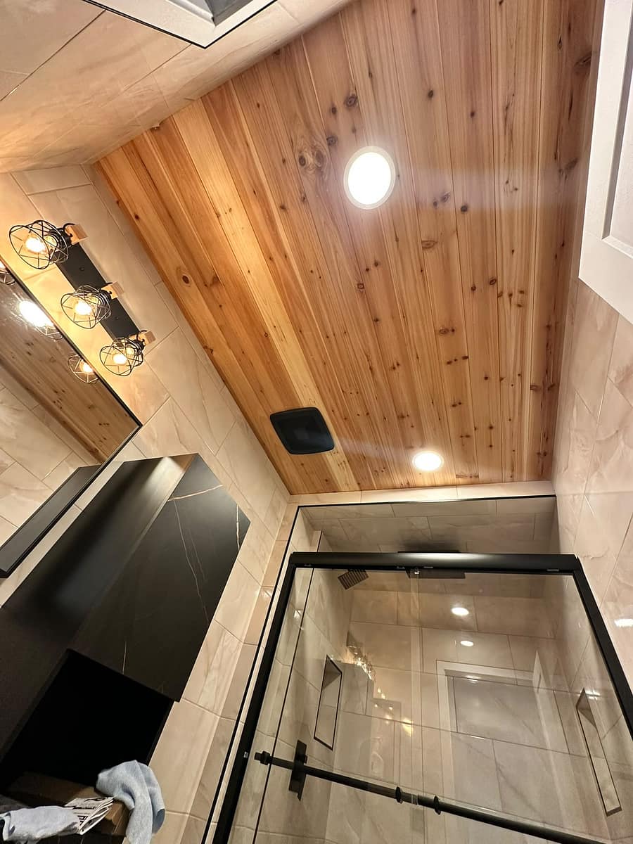 Chappelle Custom Bathroom Renovation — wide view of cedar plank ceiling, cage-style vanity lights and black-framed glass shower enclosure