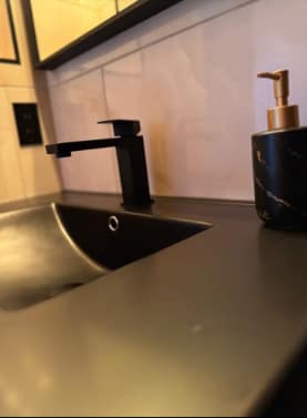 Chappelle Custom Bathroom Renovation — detail of black faucet, black sink and gold-pump soap dispenser against large-format wall tile
