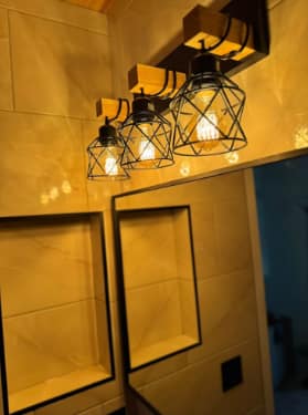 Chappelle Custom Bathroom Renovation — Edison-bulb cage vanity light fixture suspended from the wood ceiling above the black-framed mirror