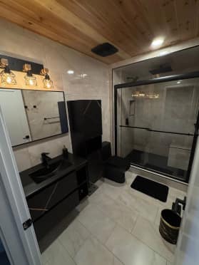 Chappelle Custom Bathroom Renovation — wide-angle view of the complete bathroom with wood ceiling, marble tile and matte-black vanity