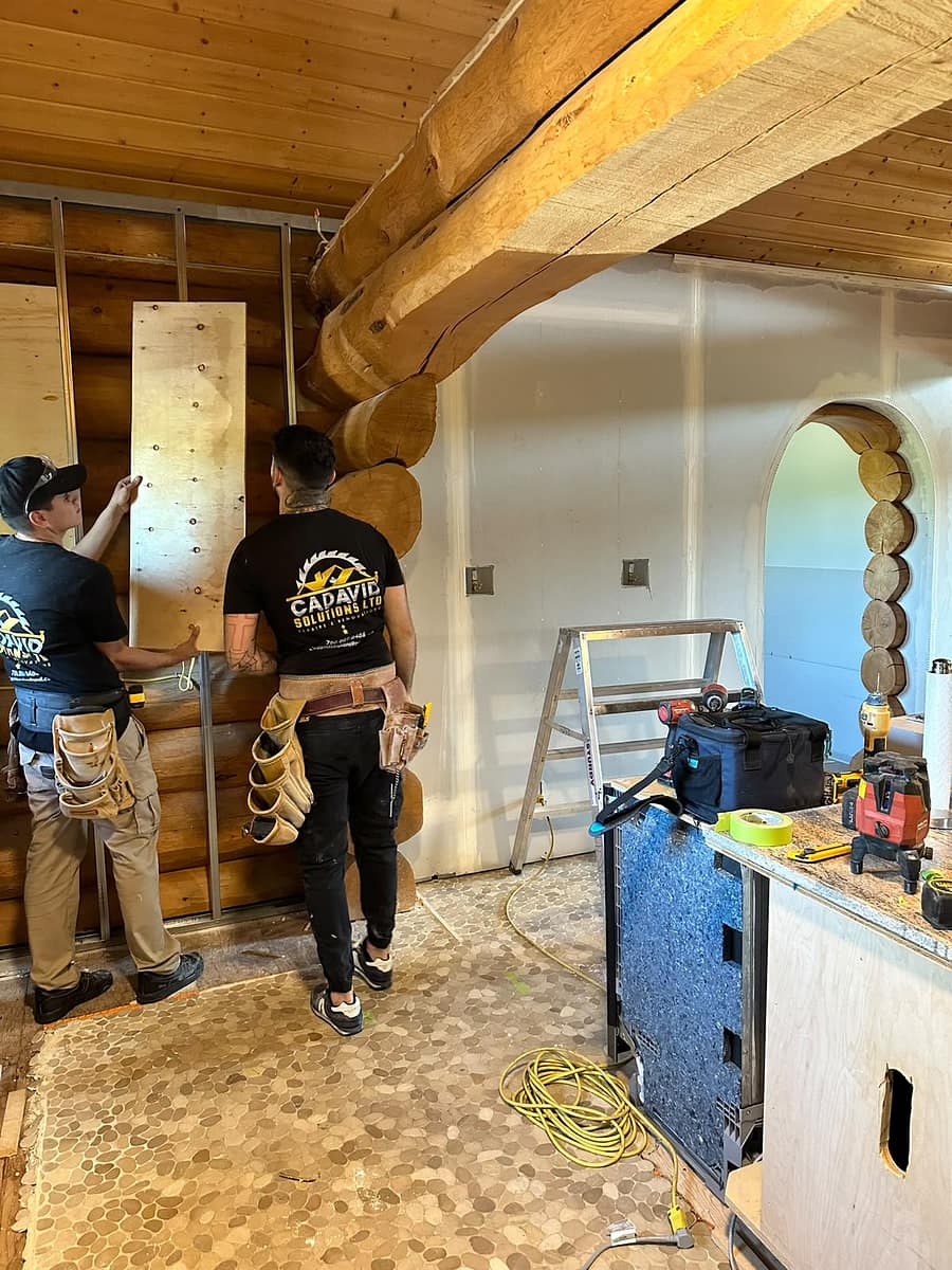 Custom Log Home Interior Renovation — Cadavid Solutions crew installing drywall and metal framing around the original log walls and arched openings