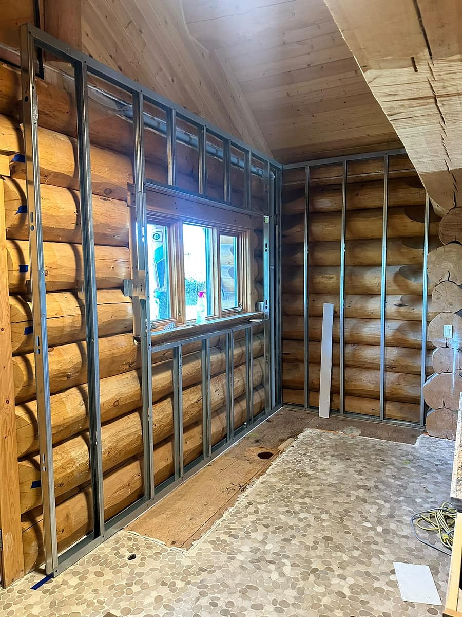 Custom Log Home Interior Renovation — metal framing installed around the original log walls