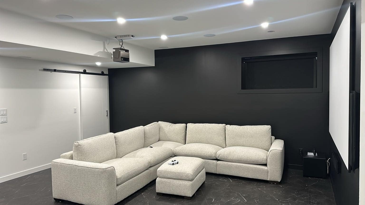 Basement Development — finished home theatre with sectional seating, projector and dark accent wall