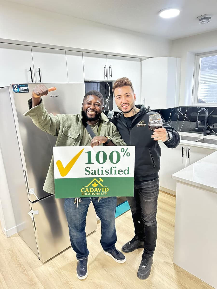 Two satisfied clients holding a 100% Satisfied sign in the finished kitchen