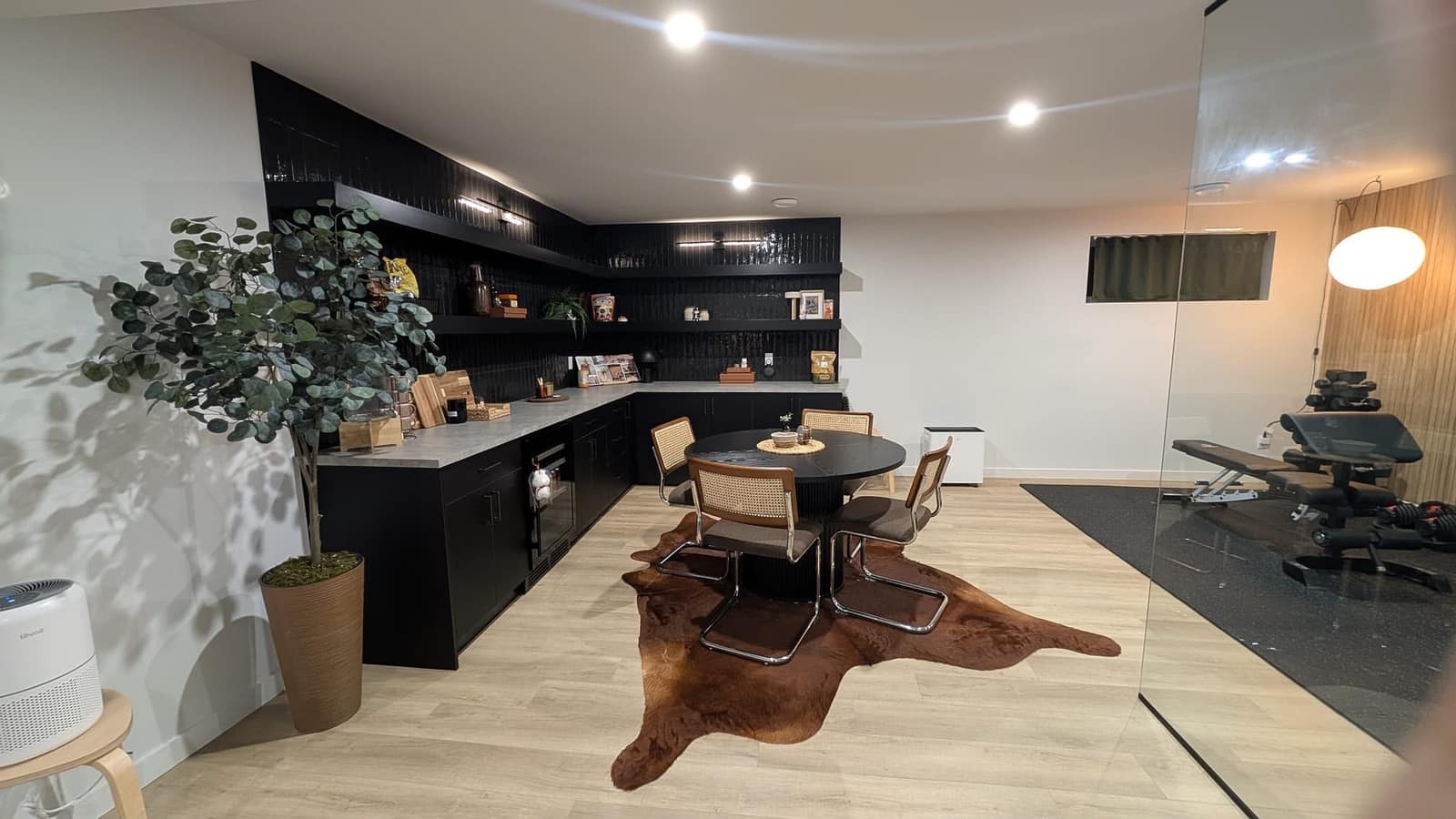 South Edmonton basement kitchen and dining area with black cabinetry, round dining table and view toward the home gym glass partition